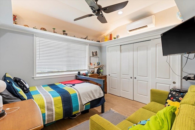 bedroom with hardwood / wood-style flooring, a closet, a wall mounted air conditioner, vaulted ceiling, and ceiling fan