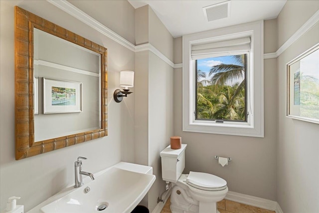 bathroom featuring toilet, plenty of natural light, a sink, and visible vents