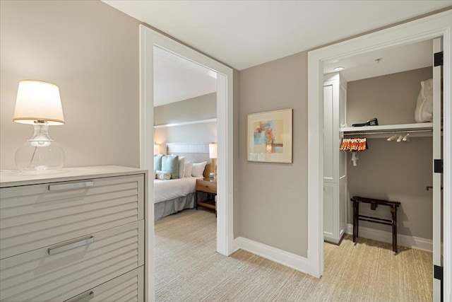 hallway featuring light carpet and baseboards