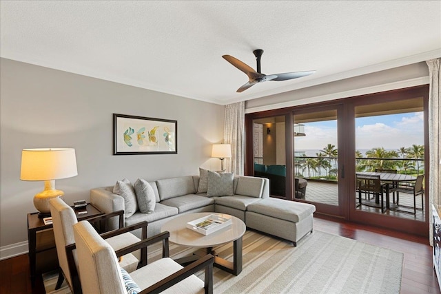 living room with ceiling fan, a textured ceiling, baseboards, and wood finished floors