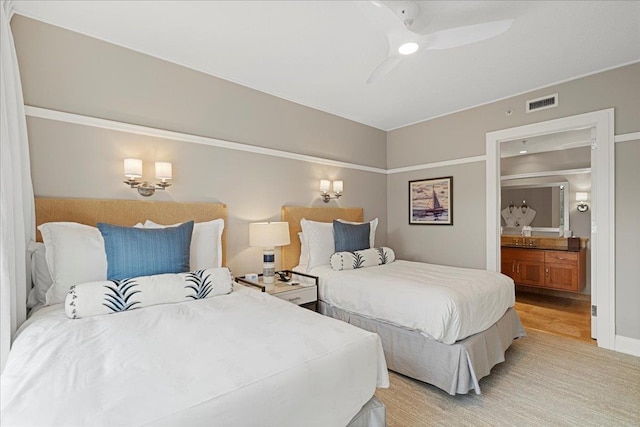 bedroom with a ceiling fan, ensuite bath, visible vents, and wood finished floors