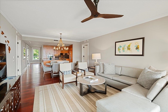 living area featuring dark wood-type flooring, visible vents, ornamental molding, and ceiling fan with notable chandelier