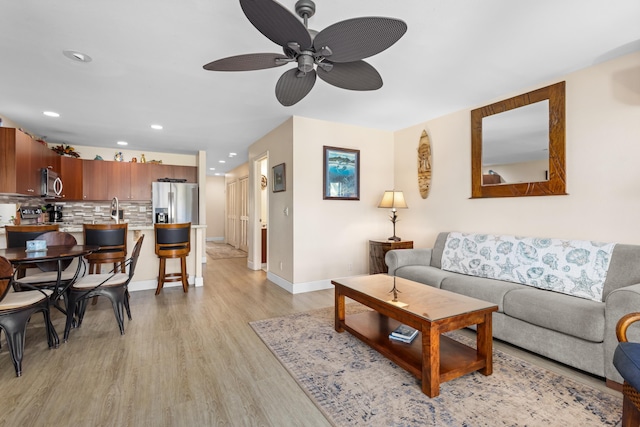 living room with light hardwood / wood-style flooring, ceiling fan, and sink