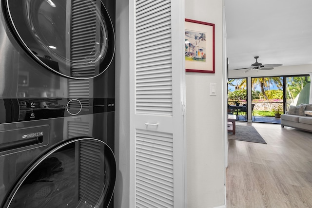 laundry area featuring stacked washer / drying machine, light hardwood / wood-style floors, and ceiling fan