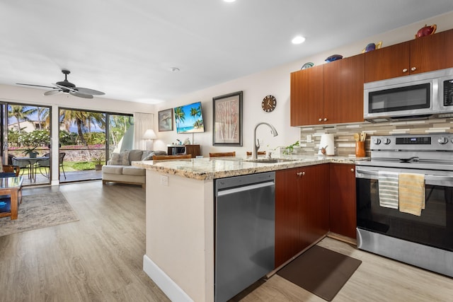 kitchen featuring ceiling fan, sink, light hardwood / wood-style flooring, kitchen peninsula, and appliances with stainless steel finishes