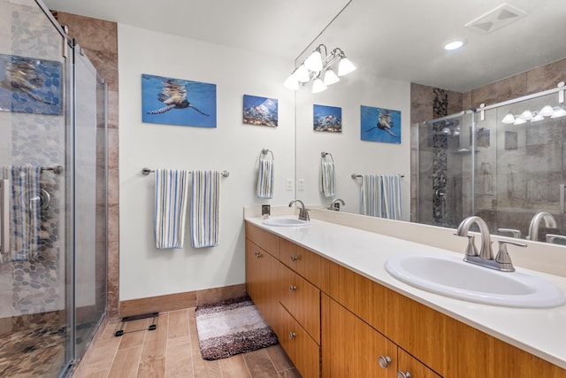 bathroom with hardwood / wood-style floors, vanity, and a shower with shower door