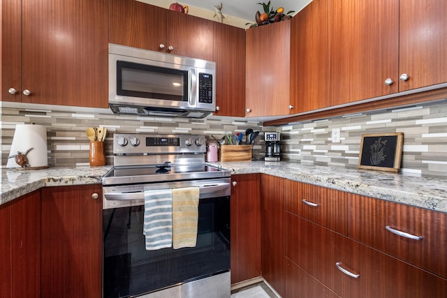 kitchen with light stone countertops, stainless steel appliances, and tasteful backsplash