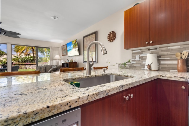 kitchen featuring stainless steel dishwasher, ceiling fan, light stone countertops, and sink