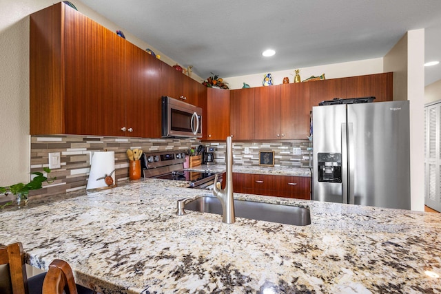 kitchen with light stone countertops, sink, tasteful backsplash, a breakfast bar, and appliances with stainless steel finishes