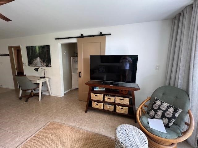 living room featuring ceiling fan, light tile patterned floors, and a barn door