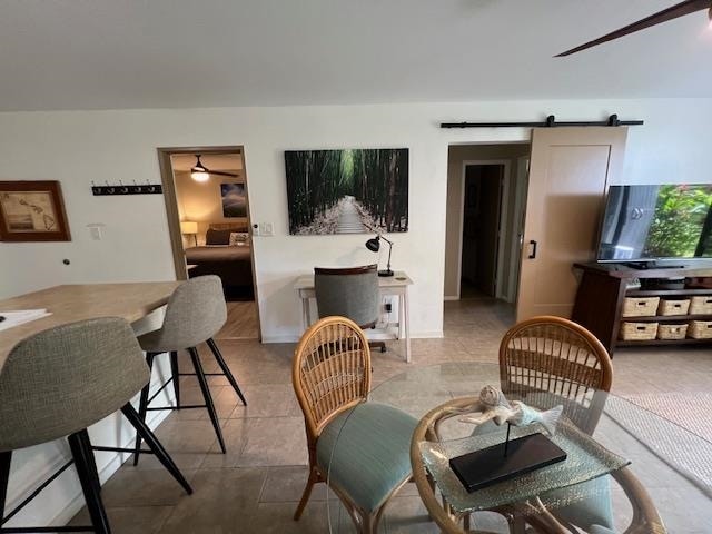 dining area featuring ceiling fan and a barn door