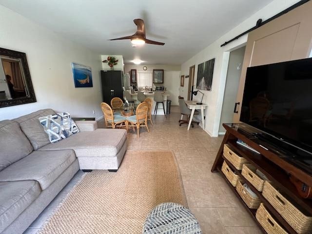 tiled living room with ceiling fan and a barn door