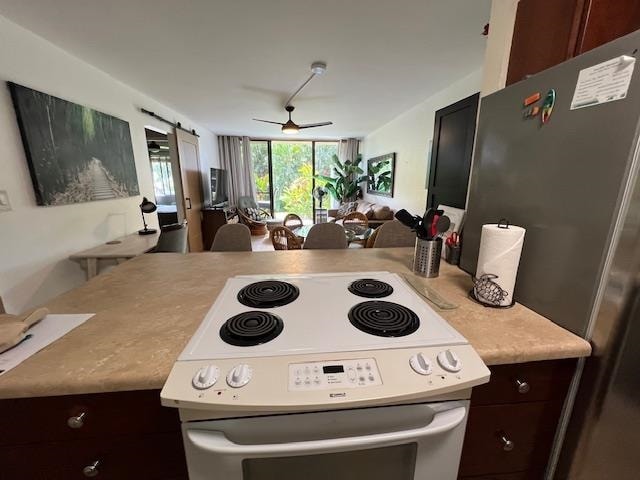 kitchen with dark brown cabinets, a barn door, white range with electric stovetop, ceiling fan, and stainless steel fridge