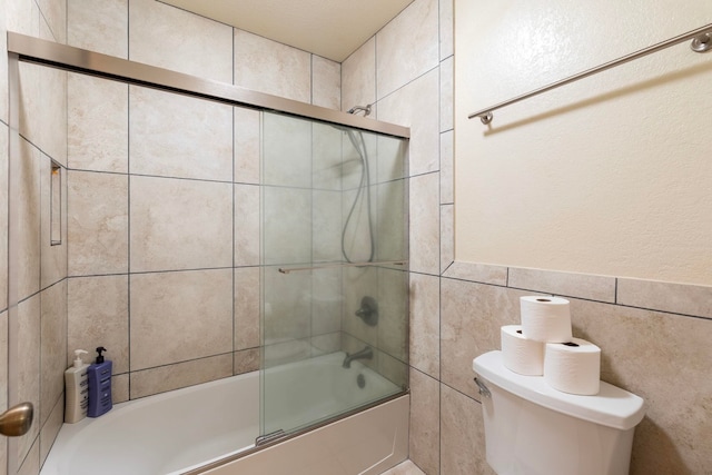 bathroom featuring shower / bath combination with glass door, tile walls, and toilet