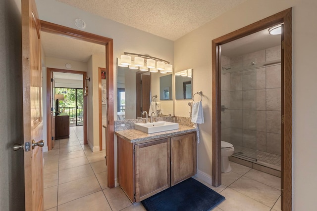 bathroom with a textured ceiling, tile patterned flooring, toilet, vanity, and a shower stall