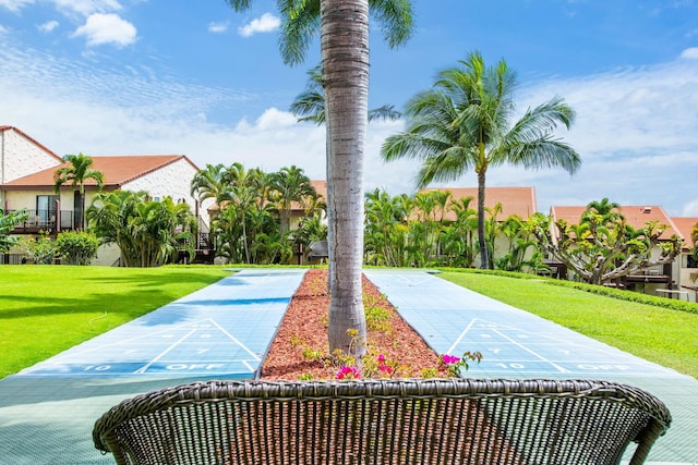 view of home's community with shuffleboard and a yard