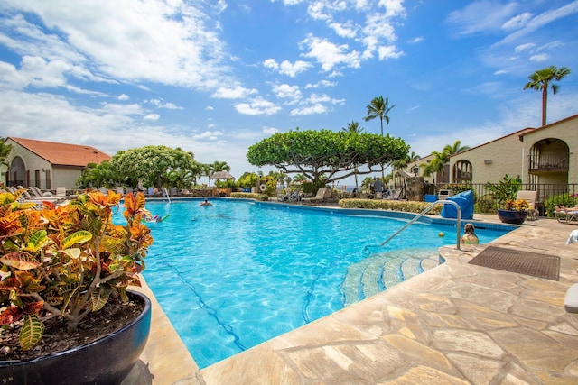 community pool with a patio area and fence