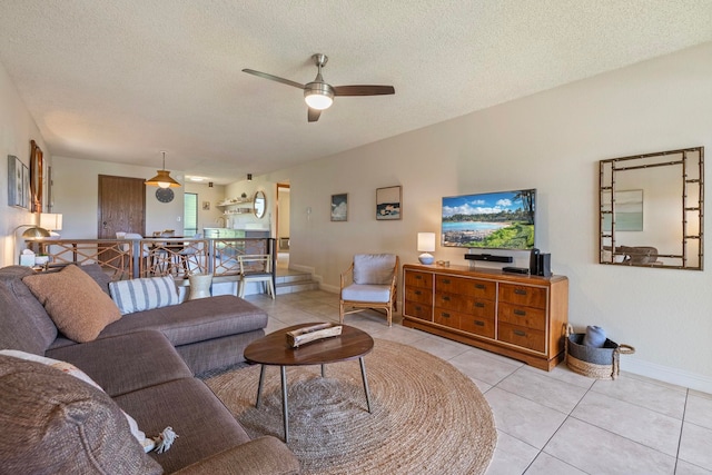 tiled living area with a textured ceiling, a ceiling fan, and baseboards