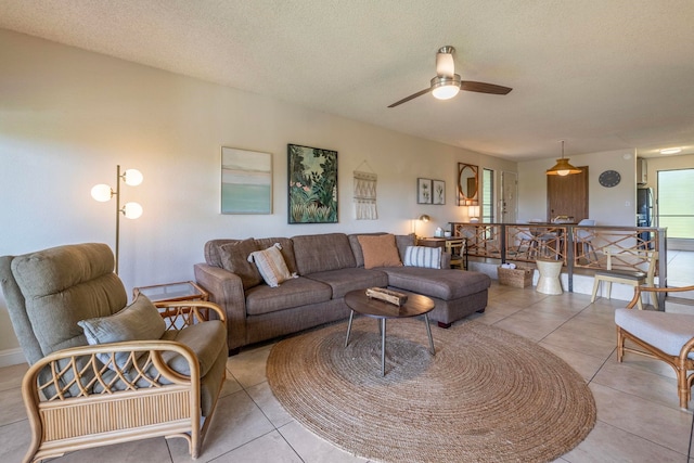 living room with ceiling fan, light tile patterned floors, and a textured ceiling