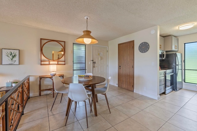 dining space with light tile patterned floors, a textured ceiling, and baseboards