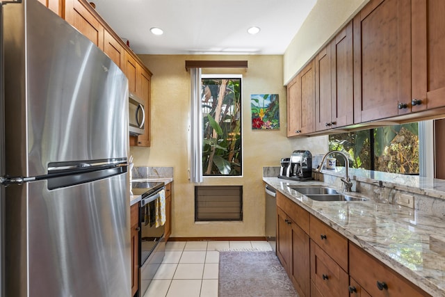 kitchen with light stone counters, sink, light tile patterned floors, and stainless steel appliances