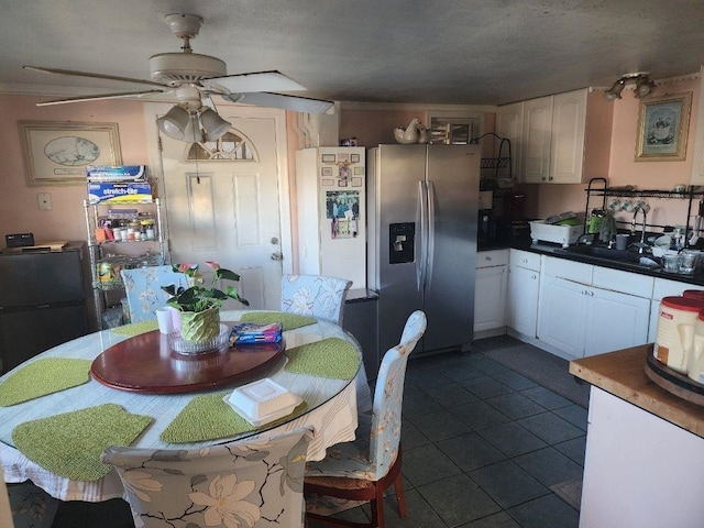 tiled dining space featuring ceiling fan, sink, a textured ceiling, and ornamental molding