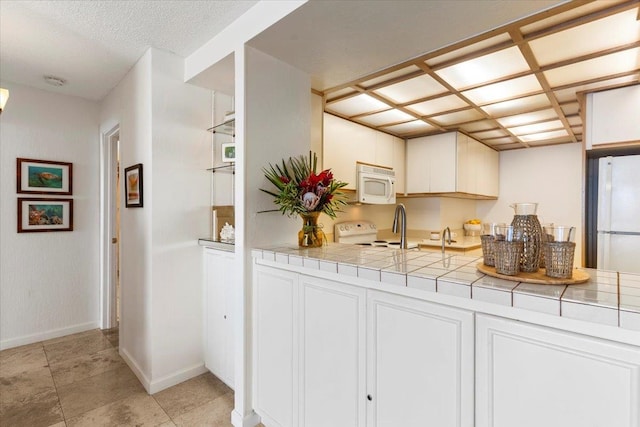 kitchen featuring white cabinetry, tile countertops, and white appliances