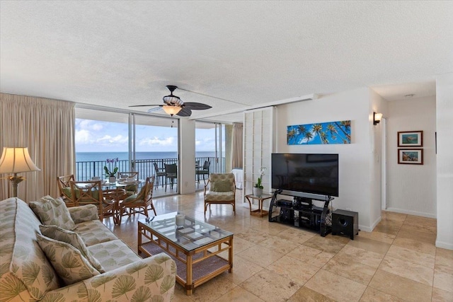 living room with a textured ceiling, baseboards, ceiling fan, and floor to ceiling windows