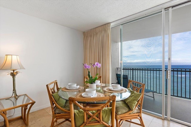dining space with a water view, a textured ceiling, floor to ceiling windows, and plenty of natural light
