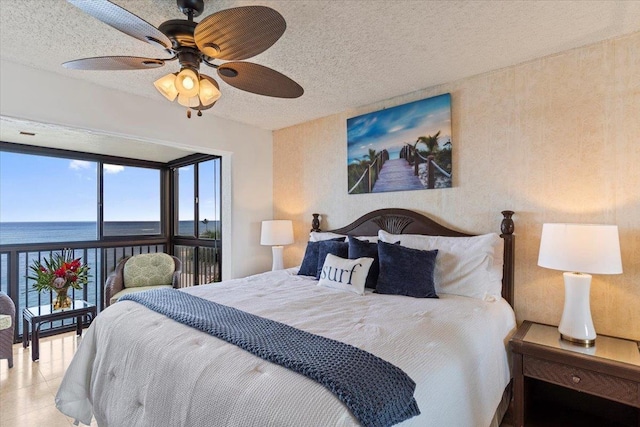 bedroom with a textured ceiling, a water view, and a ceiling fan