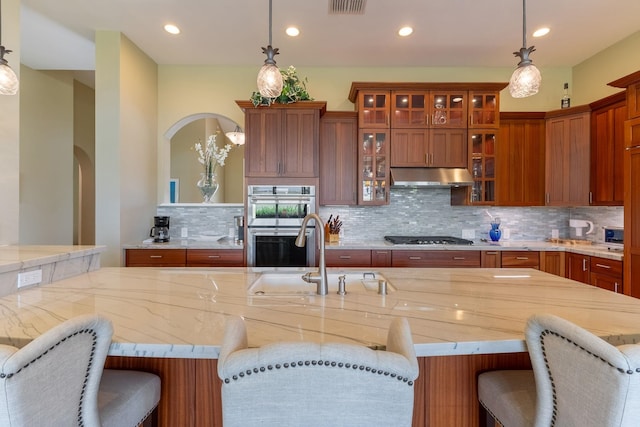 2563 Umeke Cir Unit 64, Kihei, HI 96753 - kitchen with under cabinet range hood, arched walkways, appliances with stainless steel finishes, tasteful backsplash, and a sink