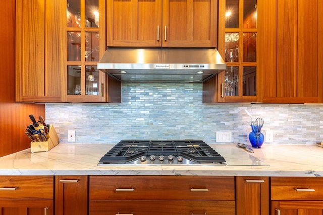 2563 Umeke Cir Unit 64, Kihei, HI 96753 - kitchen featuring under cabinet range hood, stainless steel gas cooktop, backsplash, and glass insert cabinets