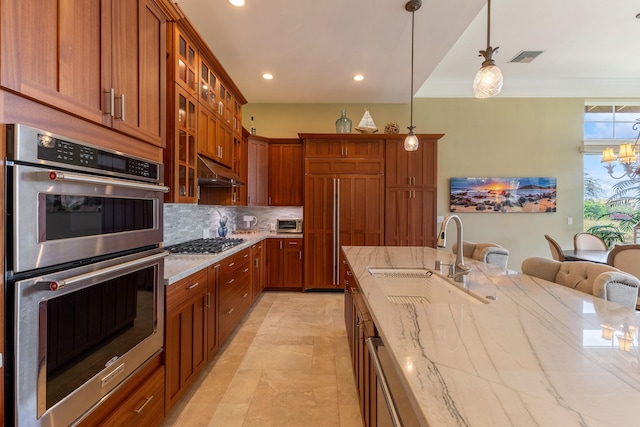 2563 Umeke Cir Unit 64, Kihei, HI 96753 - kitchen featuring appliances with stainless steel finishes, a sink, light stone countertops, backsplash, and pendant lighting