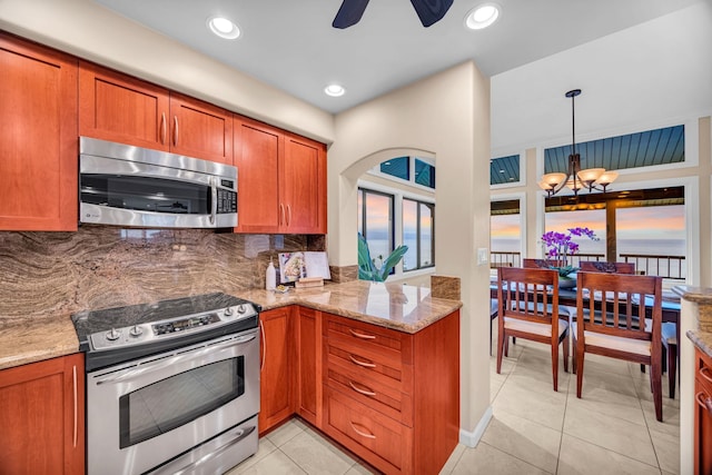 kitchen with ceiling fan with notable chandelier, backsplash, brown cabinets, and stainless steel appliances