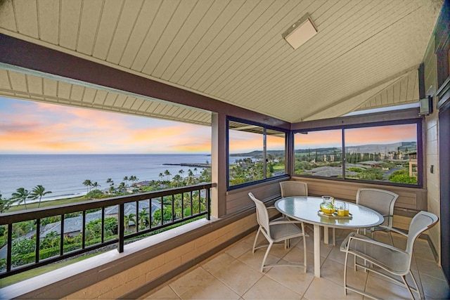balcony at dusk featuring a water view