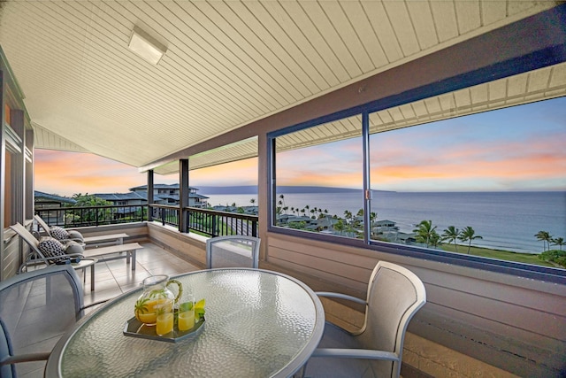 balcony with outdoor dining area and a water view