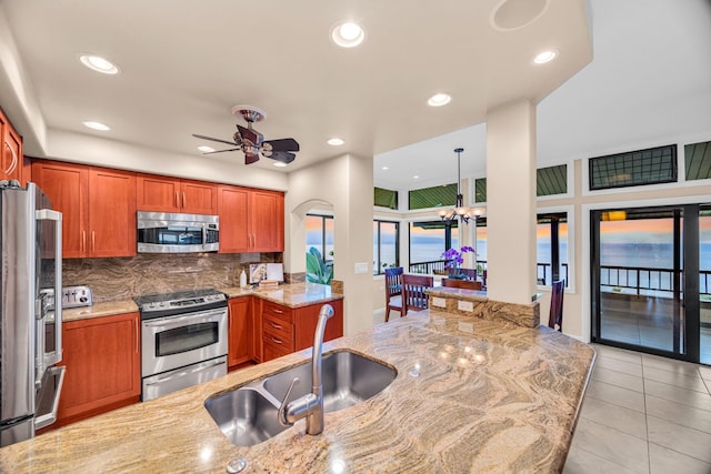 kitchen with light tile patterned floors, ceiling fan, stainless steel appliances, and brown cabinets