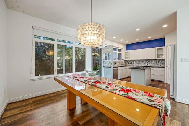 dining space featuring sink, dark wood-type flooring, and a chandelier