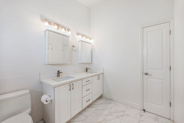 bathroom with vanity, tile walls, and toilet