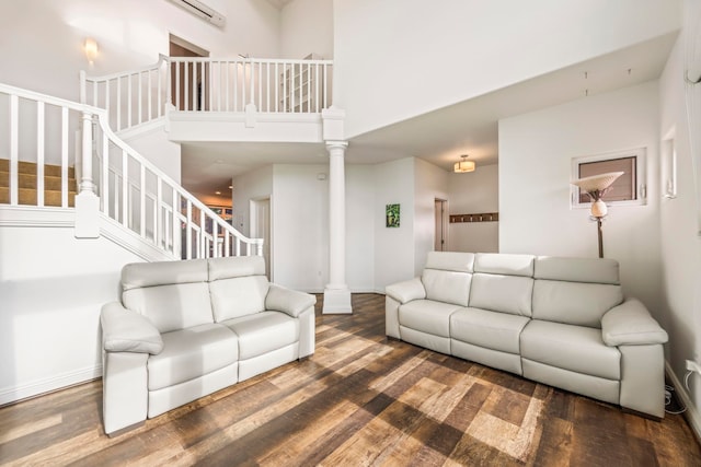 living room featuring ornate columns, wood-type flooring, and a high ceiling