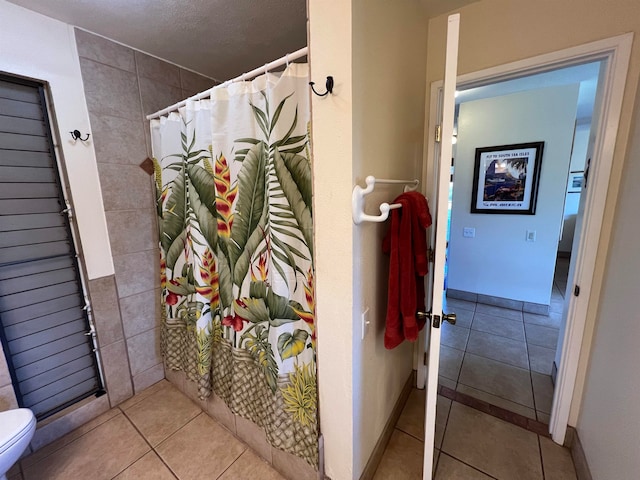 bathroom featuring walk in shower, tile patterned floors, a textured ceiling, and toilet