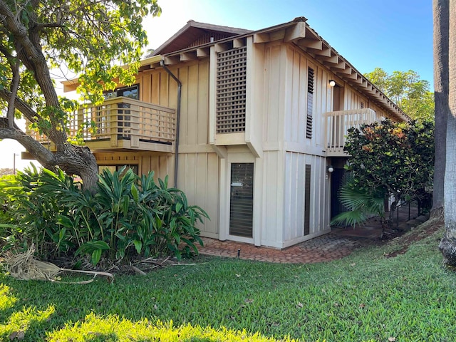 view of side of home featuring a balcony and a lawn