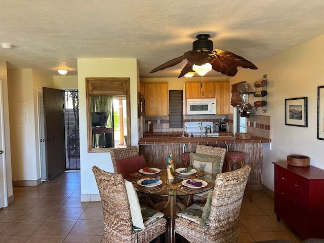 tiled dining space featuring ceiling fan and a textured ceiling