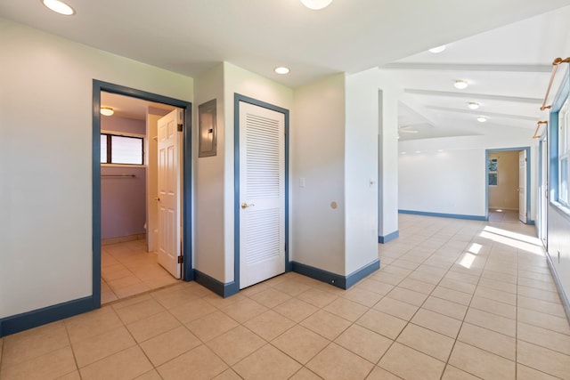 corridor featuring light tile patterned flooring and vaulted ceiling