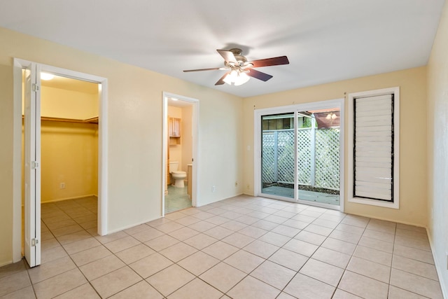 unfurnished bedroom with a spacious closet, a closet, access to outside, ceiling fan, and light tile patterned flooring