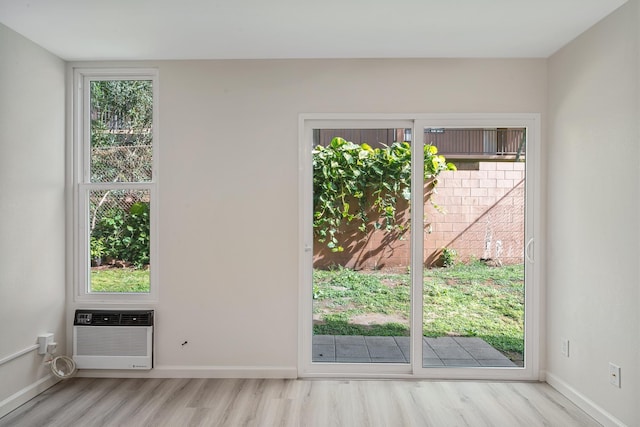 doorway to outside featuring baseboards, an AC wall unit, wood finished floors, and a healthy amount of sunlight