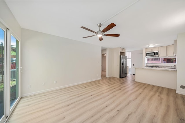 unfurnished living room featuring ceiling fan, light wood finished floors, and baseboards