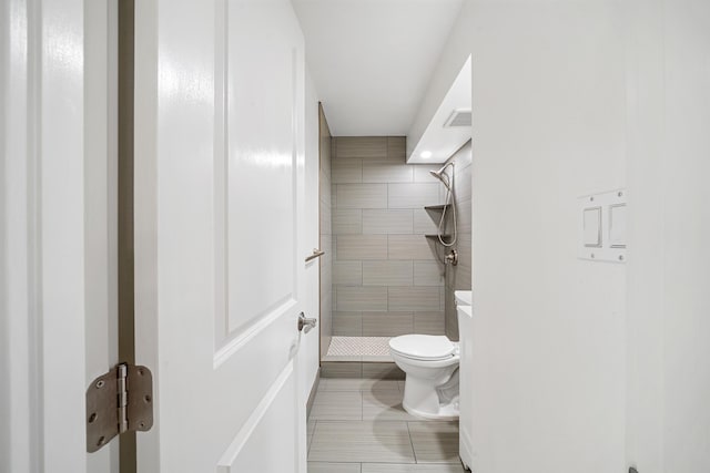 bathroom featuring visible vents, a tile shower, and toilet