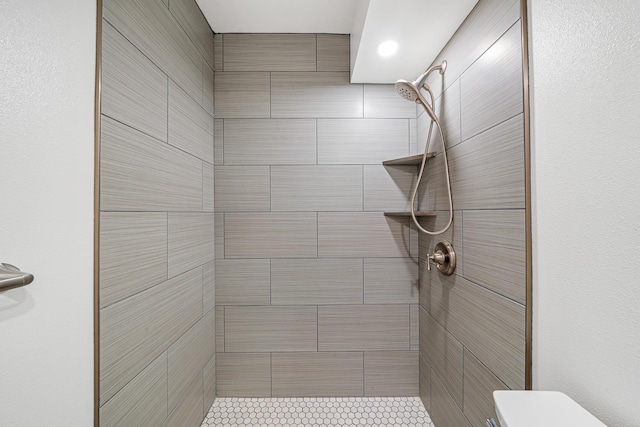 full bathroom with a tile shower and toilet