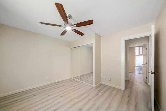 unfurnished bedroom with light wood-type flooring, a ceiling fan, baseboards, and a closet